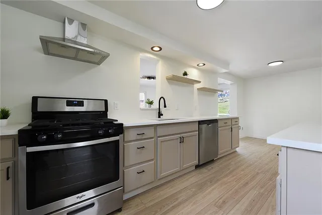 a kitchen with stainless steel appliances a stove and white cabinets