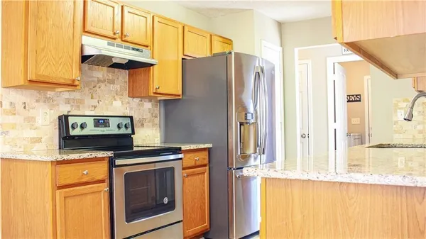 a kitchen with stainless steel appliances granite countertop a stove a sink and a refrigerator with wooden cabinets