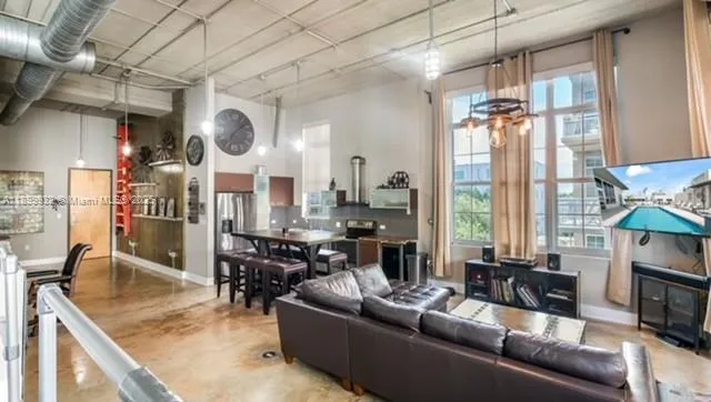 a room with lots of tables a large window and chairs