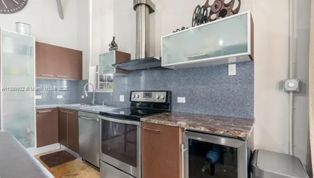 a kitchen with stainless steel appliances granite countertop a refrigerator a sink a stove and a refrigerator