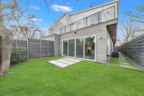 a view of a backyard with plants and large tree
