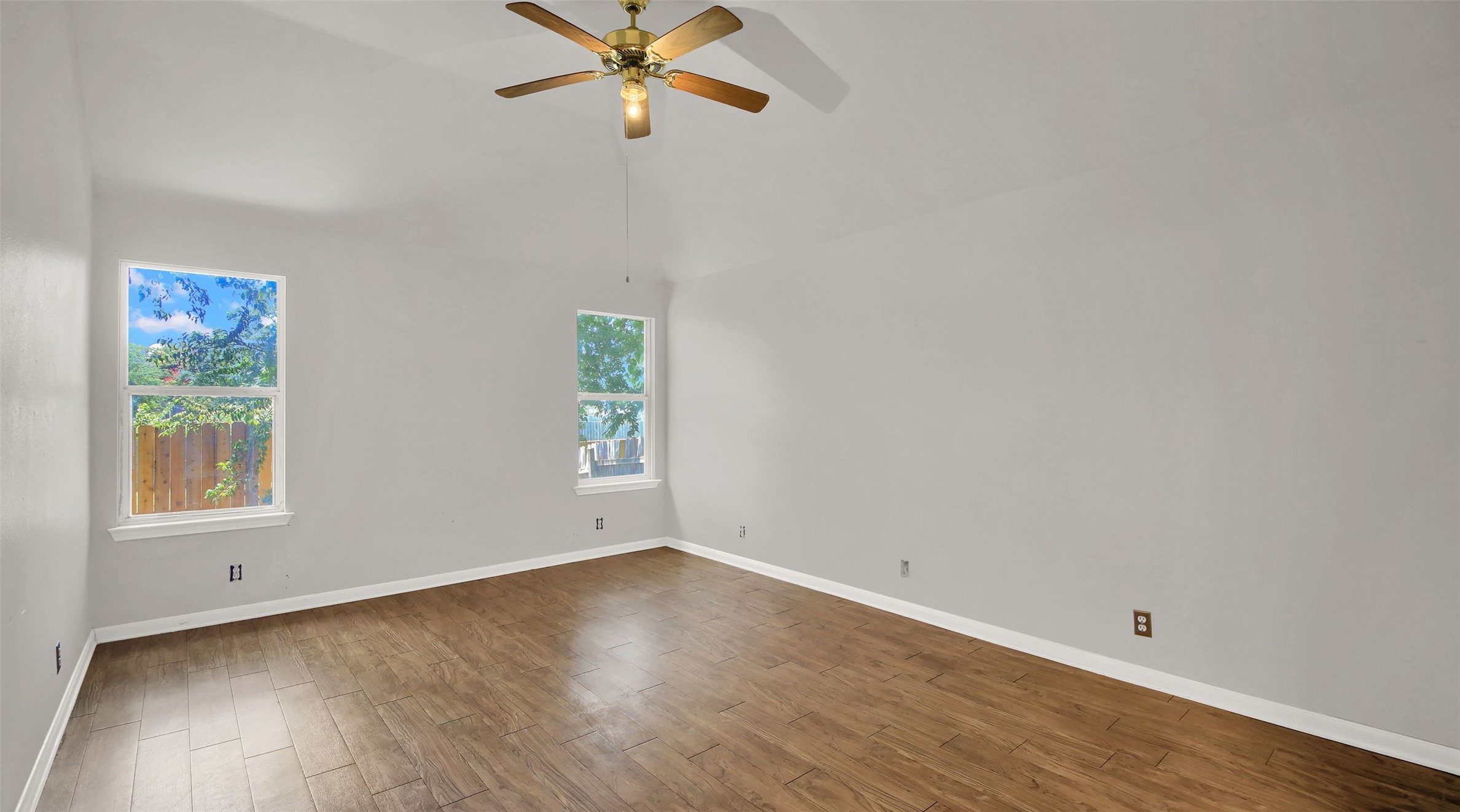 1609 Harness Raceway Street Pflugerville, TX 78660 - Photo 22 of 32 Primary Bedroom room features vaulted ceilings, rich wood flooring, and ample natural light from multiple windows.