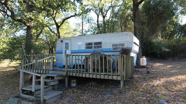 a view of a house with a wooden deck and a forest