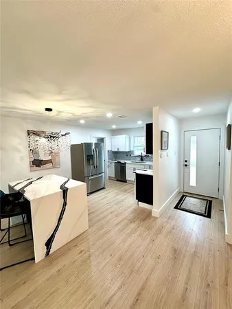 a living room with stainless steel appliances kitchen island granite countertop a sink and wooden floor