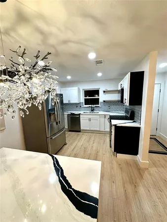 a kitchen with stainless steel appliances kitchen island granite countertop a refrigerator a stove top oven a sink with granite countertops and cabinets