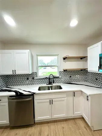 a kitchen with white cabinets and sink