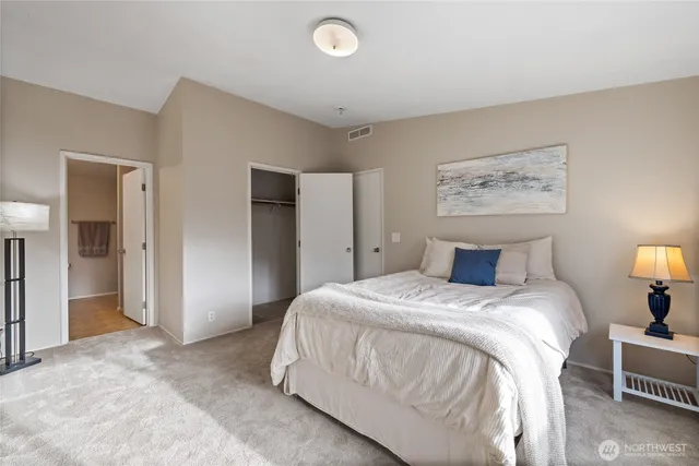 a spacious bedroom with a bed and a lamp