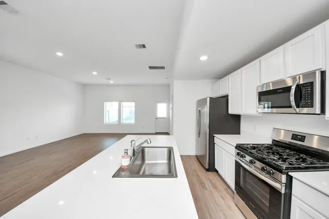 a large kitchen with stainless steel appliances granite countertop a lot of cabinets a stove and a refrigerator