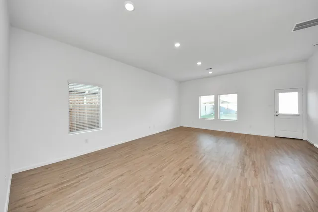 an empty room with wooden floor and windows