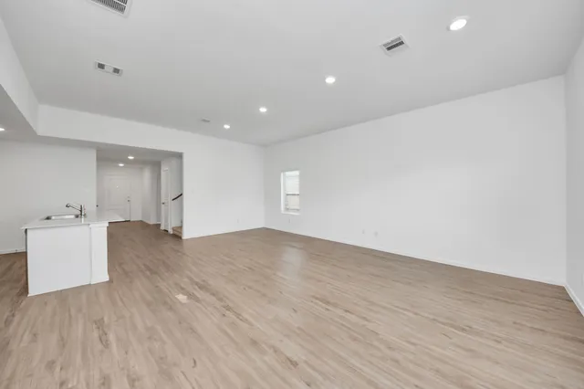 an empty room with wooden floor and sink