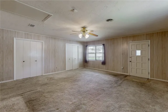 an empty room with a window and ceiling fan