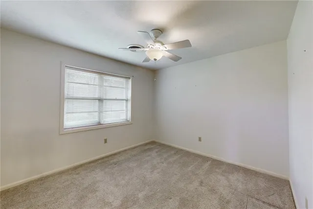 an empty room with a chandelier fan and windows