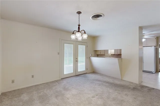 an empty room with chandelier fan and windows