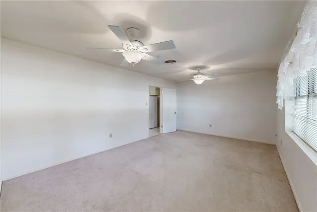 an empty room with windows and fan