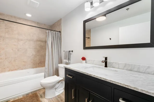 a bathroom with a granite countertop sink a toilet and a bathtub