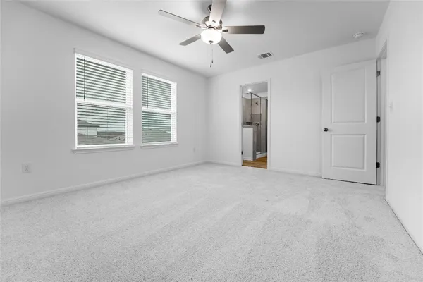 an empty room with chandelier fan and windows