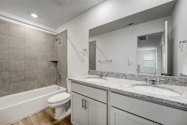 a bathroom with a granite countertop sink toilet vanity mirror bathtub and shower
