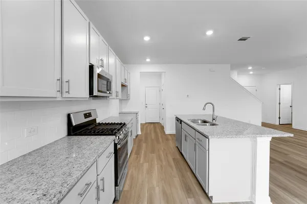 a kitchen with stainless steel appliances granite countertop a sink stove and cabinets