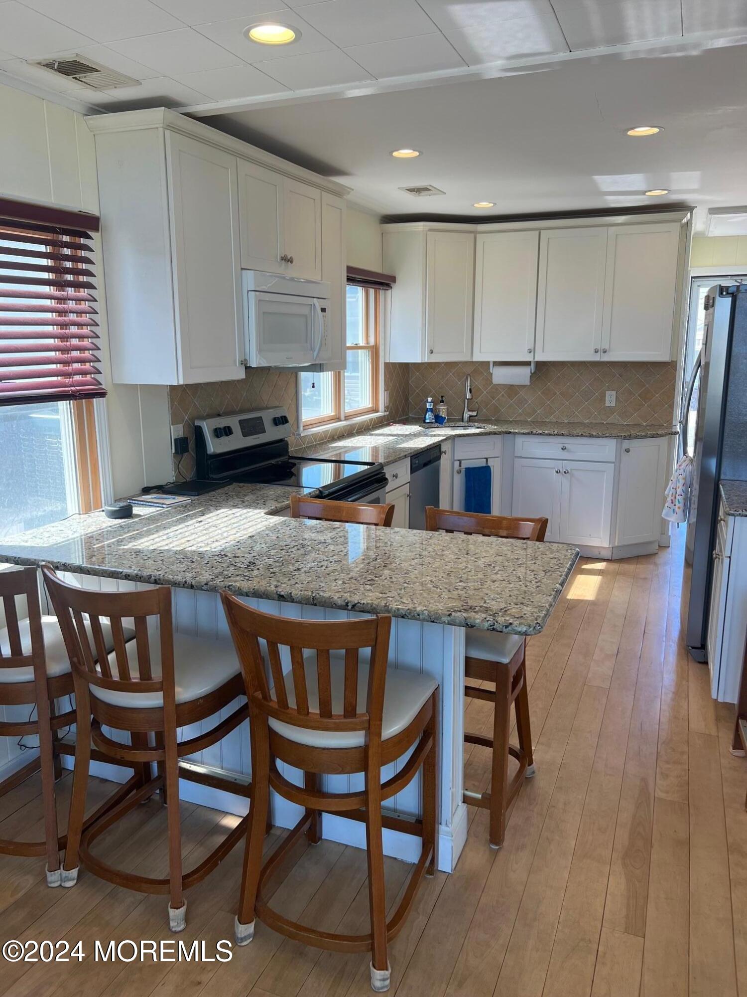 3164 Ocean Road Lavallette, NJ 08735 - Photo 7 of 14 a kitchen with stainless steel appliances granite countertop a table chairs sink refrigerator and cabinets