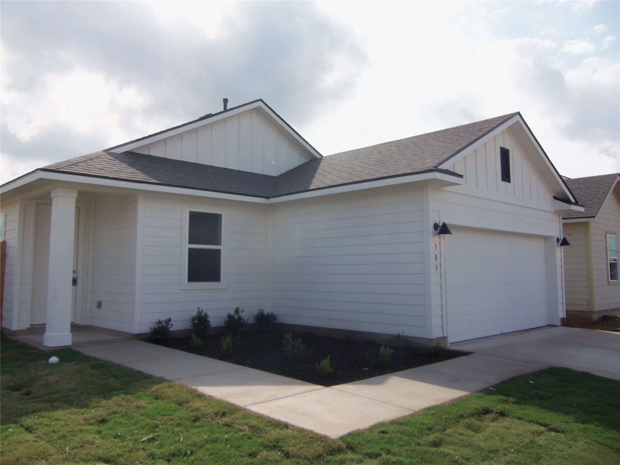 303 Cold Springs Loop Bastrop, TX 78602 - Photo 2 of 13 A well-maintained facade features crisp white siding, a welcoming entryway, and an integrated garage.