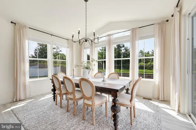 a view of a dining room and livingroom with furniture wooden floor a chandelier