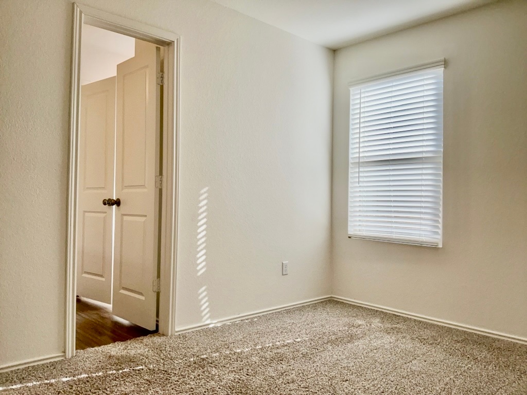 101 COSMOS Lane, Unit 32K Jarrell, TX 76537 - Photo 11 of 20 Carpeted bedroom with baseboards and window.