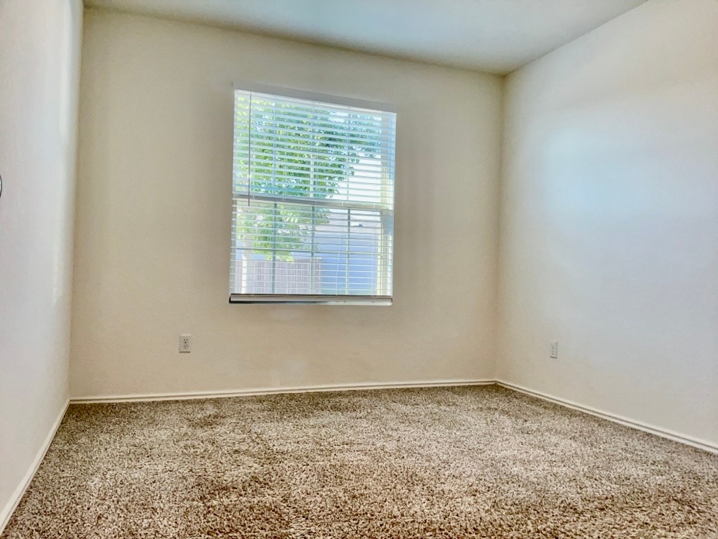 101 COSMOS Lane, Unit 32K Jarrell, TX 76537 - Photo 17 of 20 Bedroom featuring baseboards and large window.