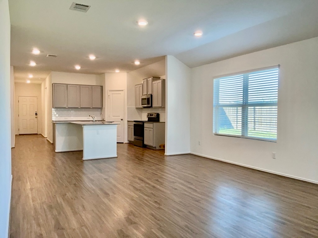 101 COSMOS Lane, Unit 32K Jarrell, TX 76537 - Photo 4 of 20 Kitchen featuring dark wood-style flooring, appliances with stainless steel finishes, tasteful backsplash, a center island with sink, and gray cabinetry