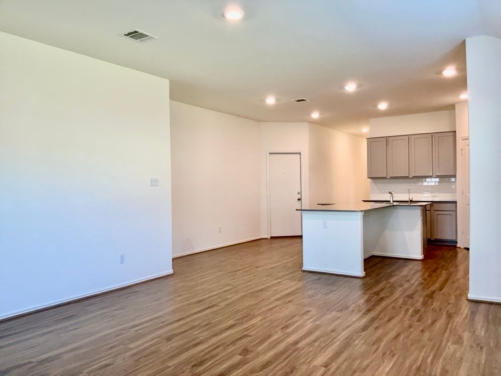 101 COSMOS Lane, Unit 32K Jarrell, TX 76537 - Photo 5 of 20 Kitchen with gray cabinetry, dark countertops, dark wood-type flooring, backsplash, and a center island with sink
