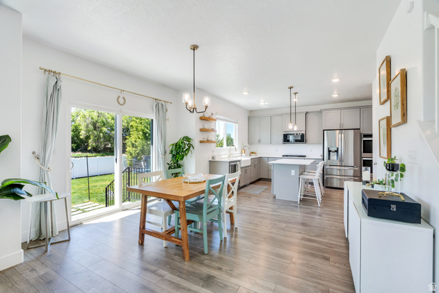 646 South Meade Street Mapleton, UT 84664 - Photo 6 of 46 Open-concept living area featuring wood-finish flooring throughout, a modern kitchen with light gray cabinetry and stainless steel appliances, and a central island with bar seating