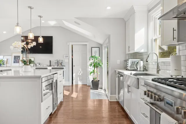 a kitchen with stainless steel appliances a stove top oven a sink a refrigerator and white cabinets