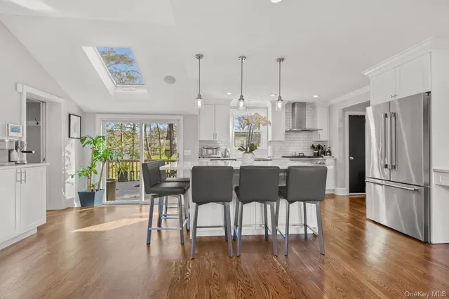 a kitchen with stainless steel appliances granite countertop a dining table chairs refrigerator and sink