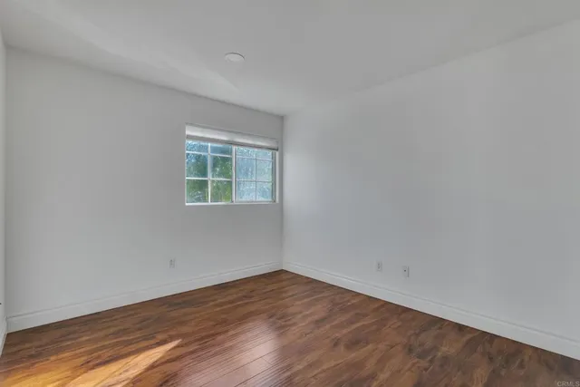 a view of an empty room with wooden floor and closet