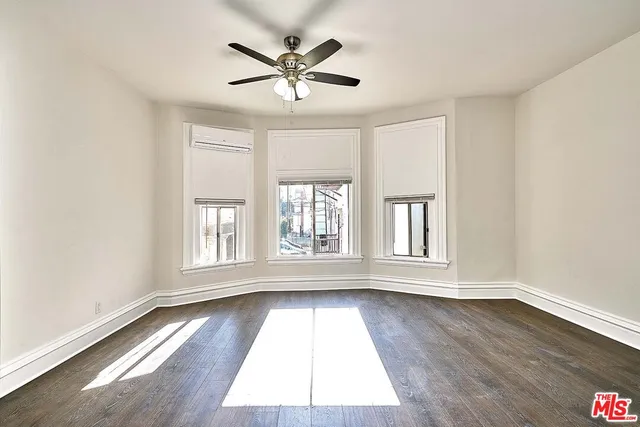 a kitchen with stainless steel appliances granite countertop a refrigerator a stove a sink and white cabinets with wooden floor next to windows