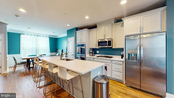 a kitchen with stainless steel appliances a refrigerator sink stove dining table and chairs