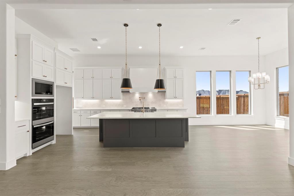 4416 Meander Way Prosper, TX 75078 - Photo 11 of 40 a large kitchen with kitchen island a sink stainless steel appliances and cabinets
