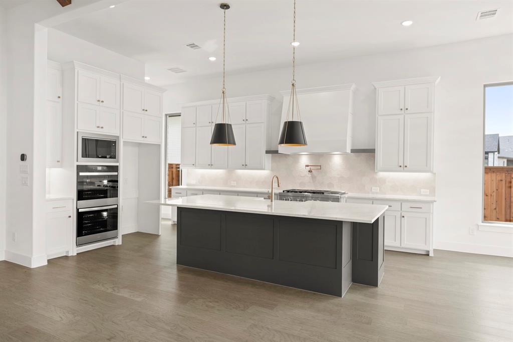 4416 Meander Way Prosper, TX 75078 - Photo 14 of 40 a kitchen with kitchen island a sink stainless steel appliances and cabinets
