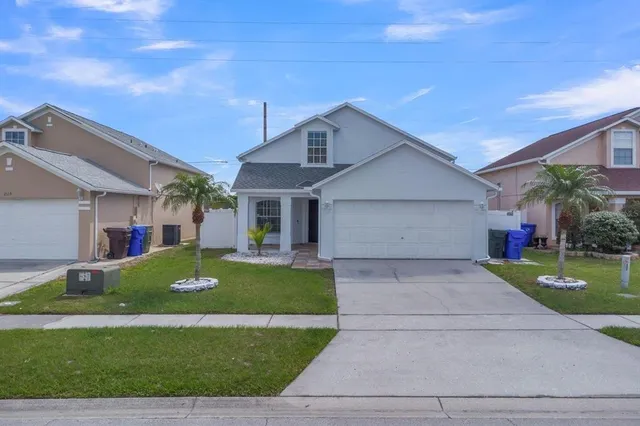 a front view of a house with garden and trees
