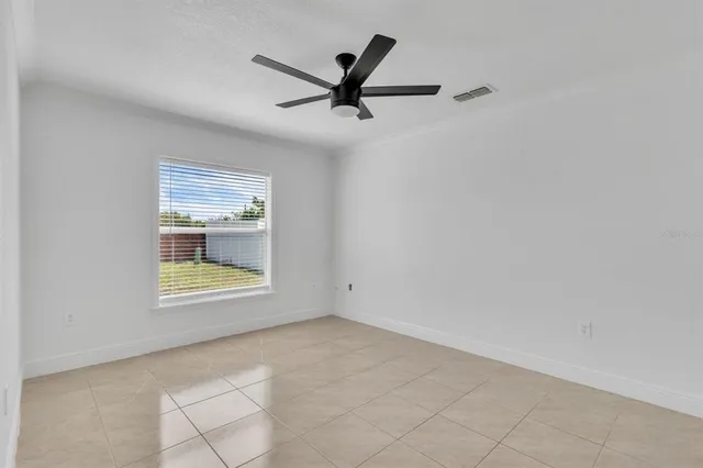 an empty room with windows and ceiling fan