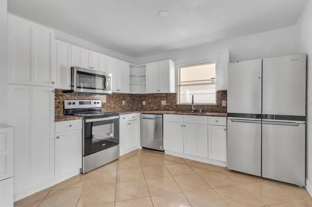 a kitchen with cabinets stainless steel appliances and a window