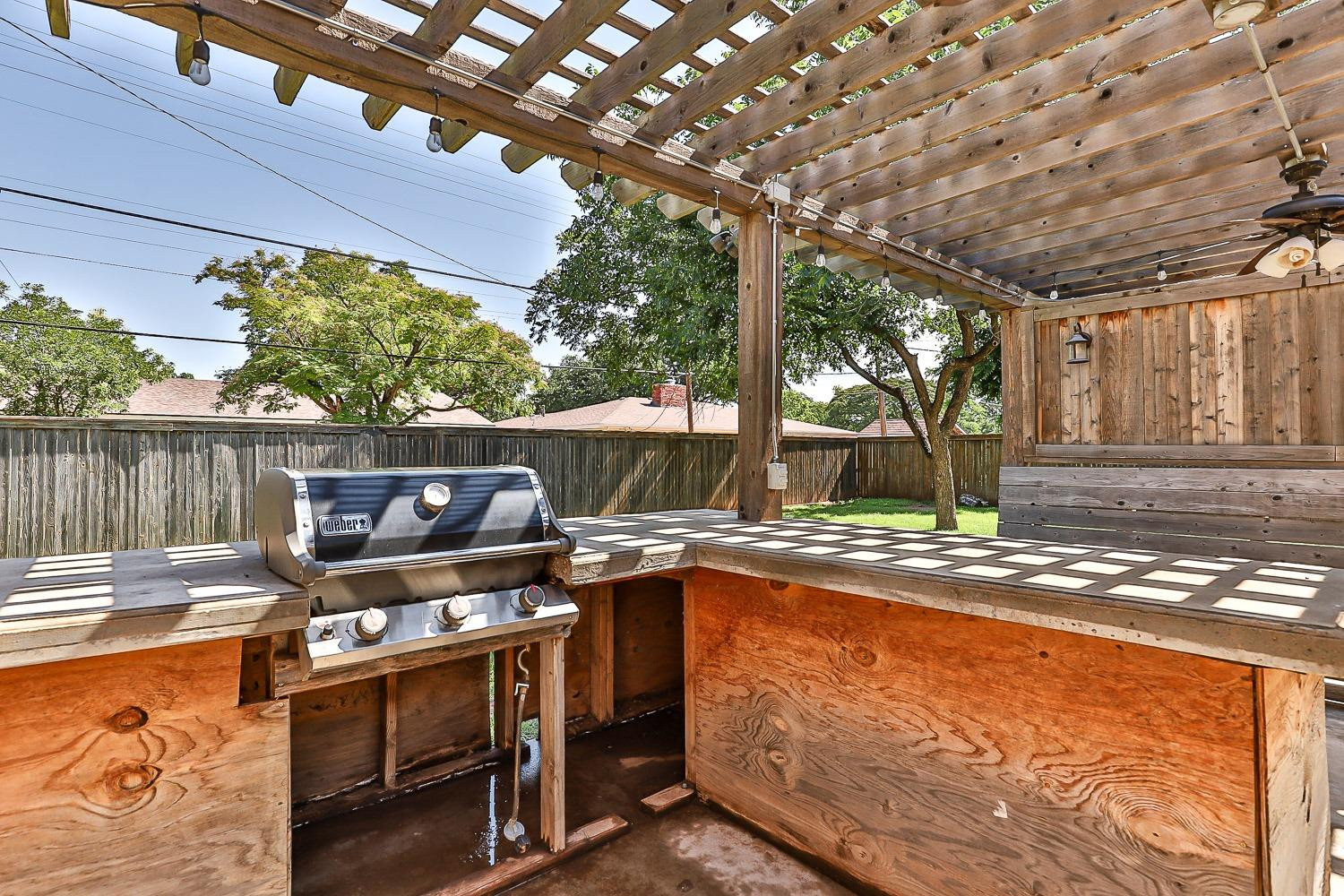 3604 48th Street Lubbock, TX 79413 - Photo 39 of 50 a view of a patio with table and chairs potted plants with wooden floor and fence