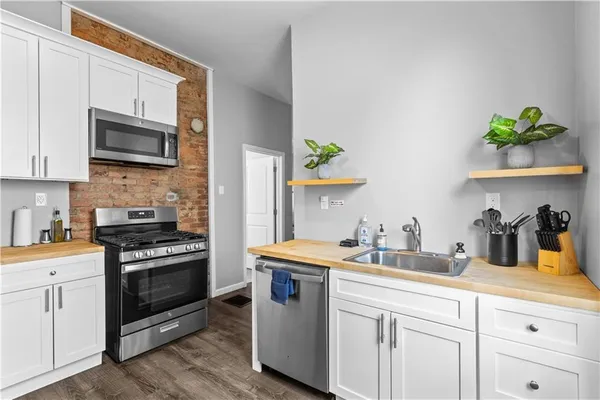 a kitchen with stainless steel appliances granite countertop a sink a stove and microwave