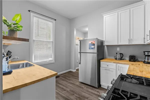 a utility room with refrigerator and wooden floor