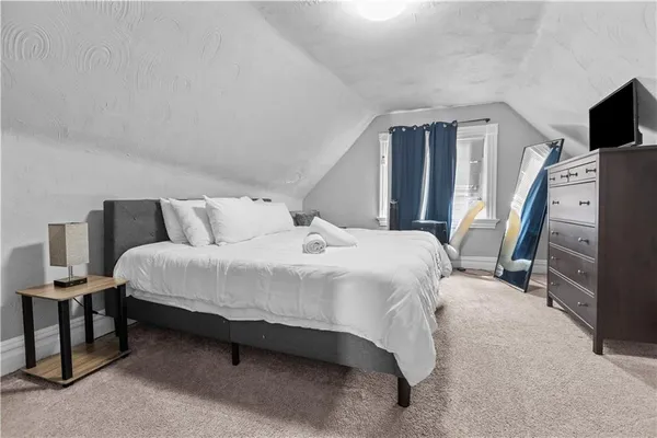 a bedroom with a bed and a flat tv screen on a dresser