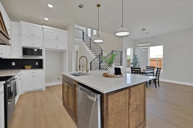 a kitchen with stainless steel appliances granite countertop a sink a stove and a wooden floors
