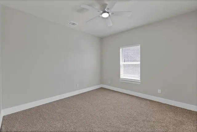 an empty room with a window and ceiling fan