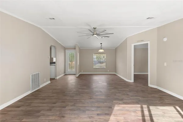 a view of an empty room with window and wooden floor