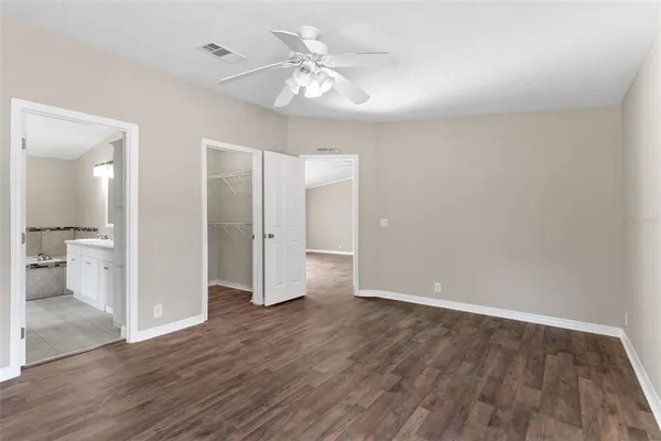 an empty room with wooden floor and a ceiling fan