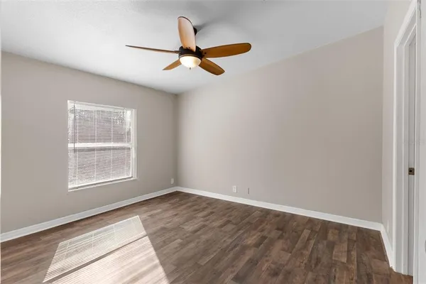 an empty room with wooden floor ceiling fan and windows