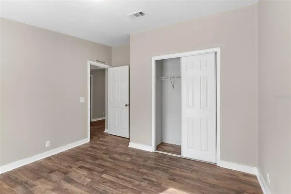 a view of an empty room with wooden floor and closet